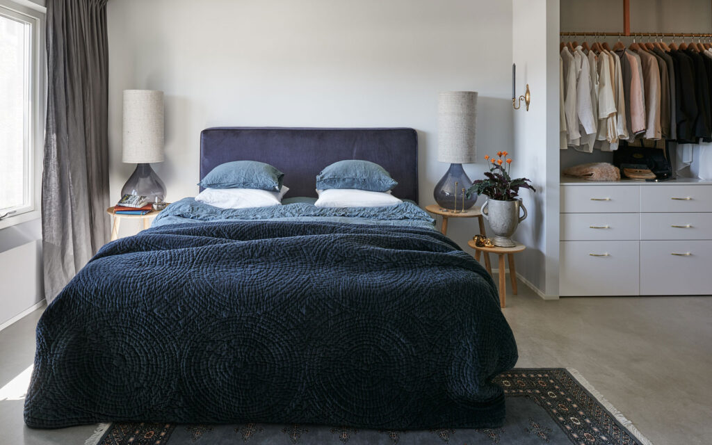 Heads and tails 3 Stor säng med överkast i djupblå sammet, inger en lyxig känsla invid den öppna garderoben och den moderna, ljusa inredningen.